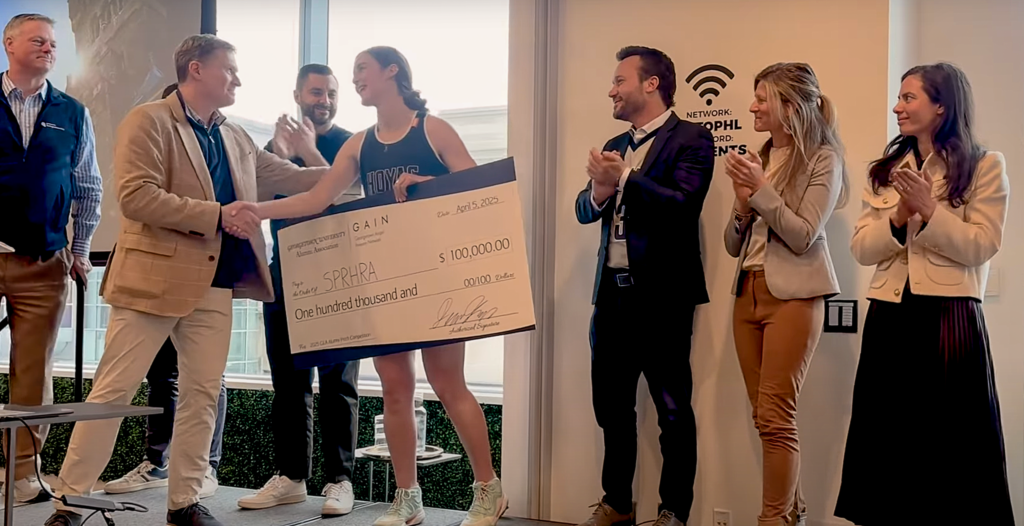 people receive a giant check and shake hands with a presenter
