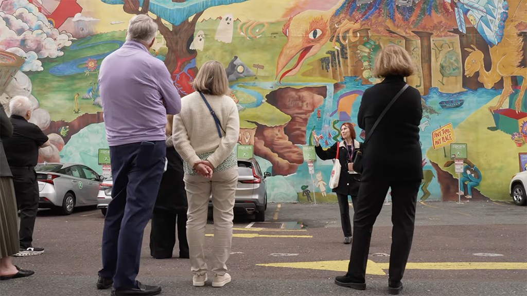 people look at a mural on the side of a building